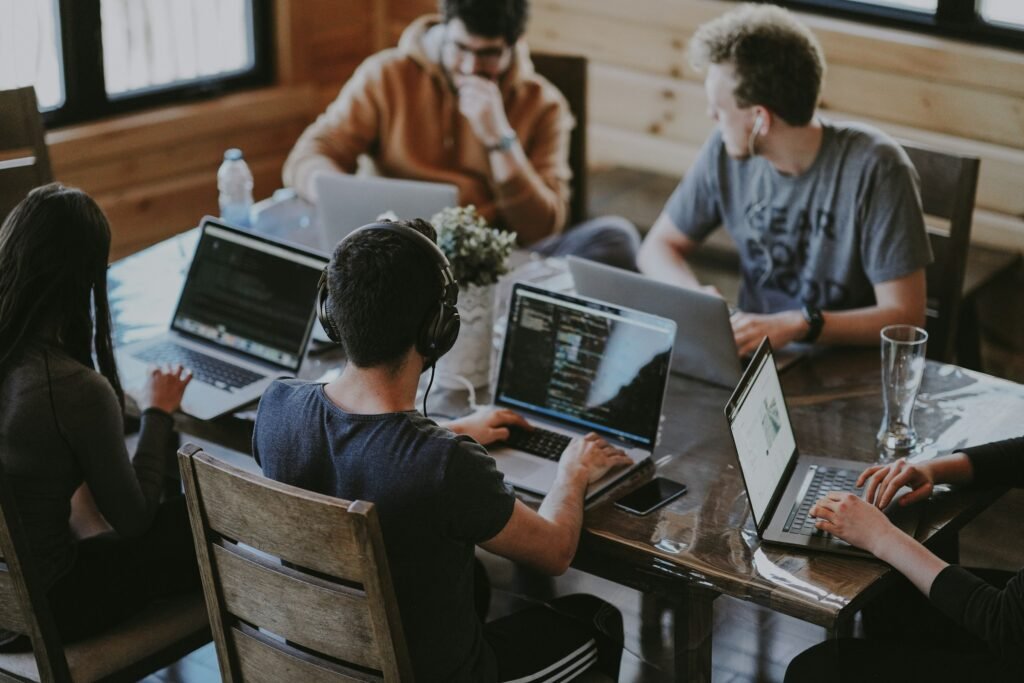 Small team of founders and early employees collaborating around a laptop in an early-stage startup workspace