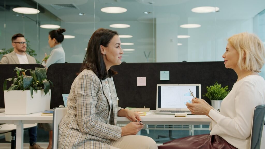 Two colleagues engaged in a thoughtful conversation at a desk, one listening closely to the other
