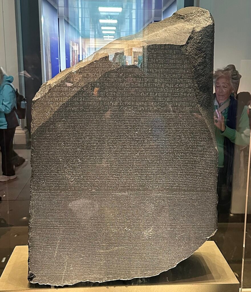 The Rosetta Stone on display at the British Museum, showing the same decree carved in Egyptian hieroglyphic, Demotic, and ancient Greek script.