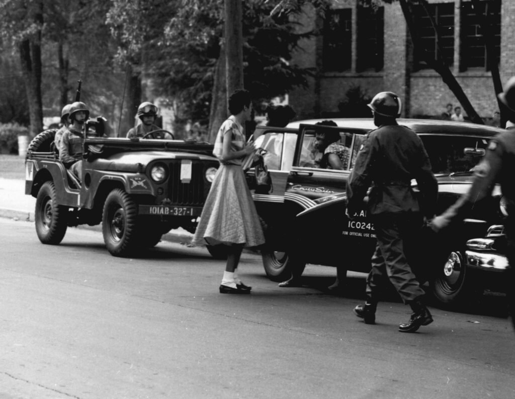 Armed U.S. Army soldiers of the 101st Airborne Division escort Black students through a crowd toward Little Rock Central High School in September 1957.