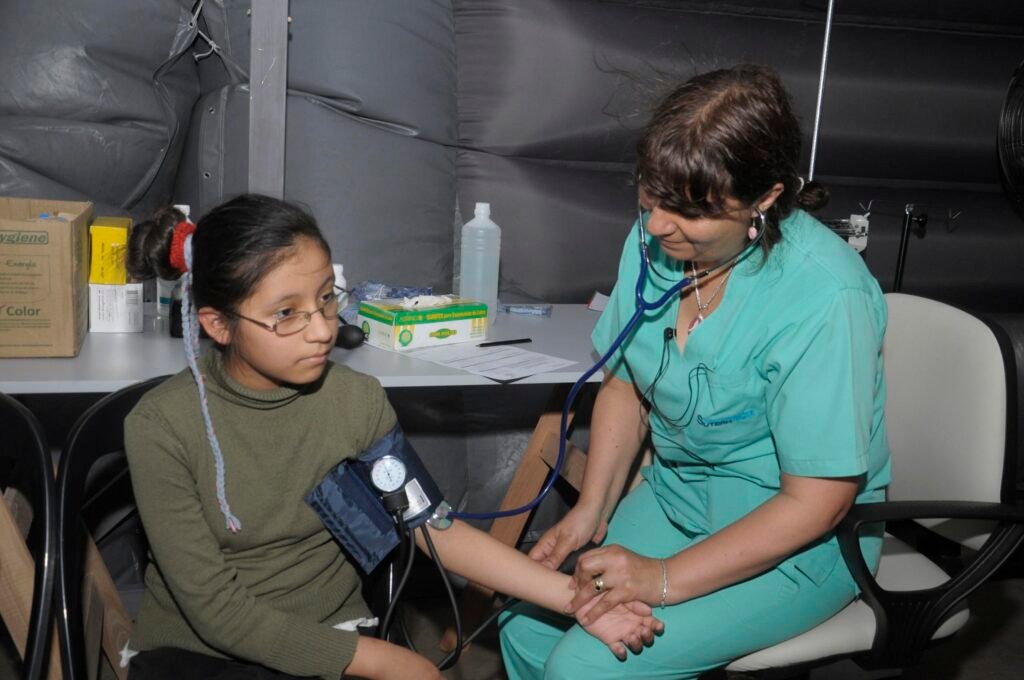 A healthcare provider measuring blood pressure with a sphygmomanometer cuff, illustrating what causes high blood pressure