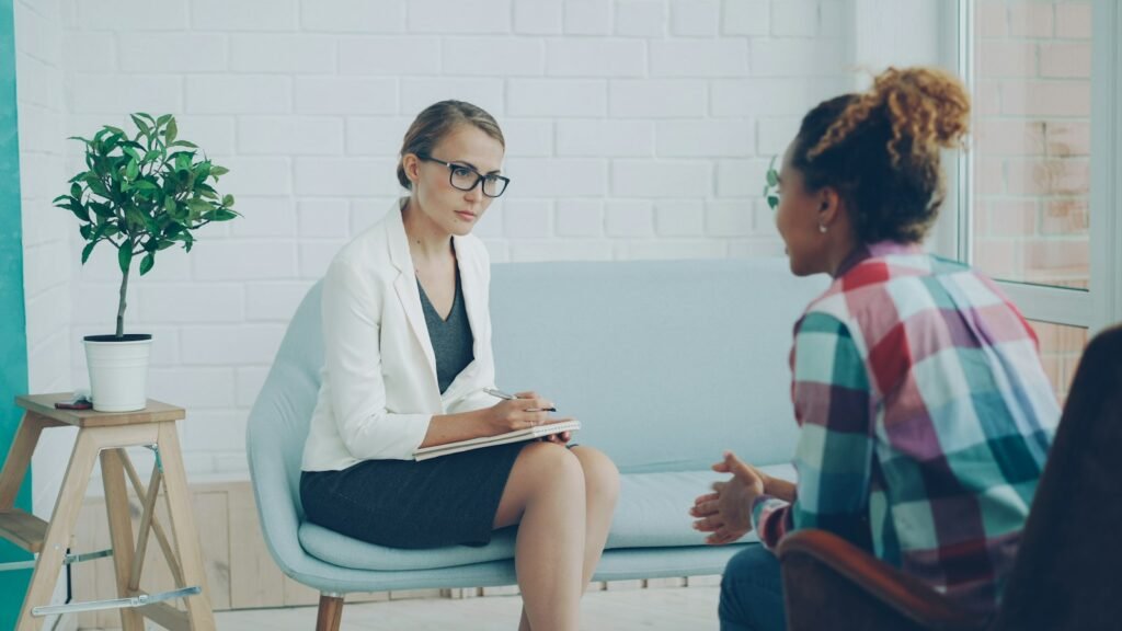 A therapist listening and taking notes during a session with a client