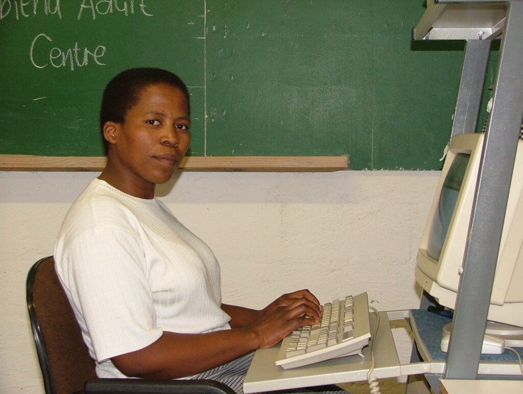A teacher working through written work beside an adult learner during a class.