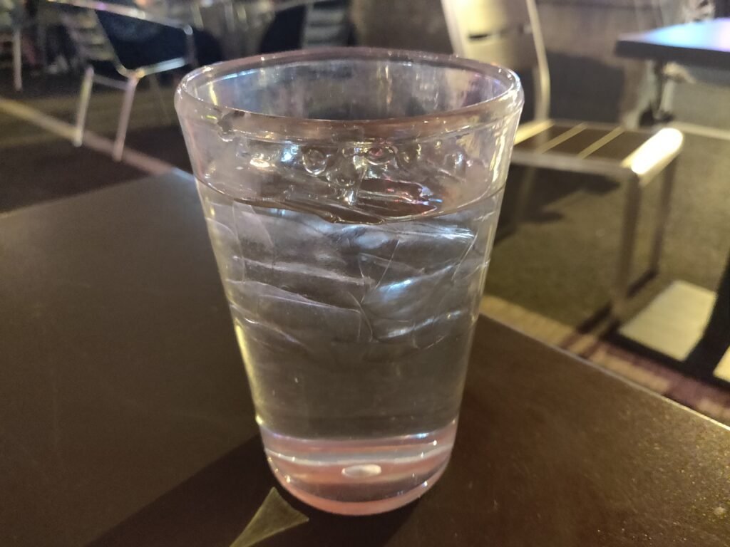 A clear glass of water sitting outdoors, representing daily hydration.