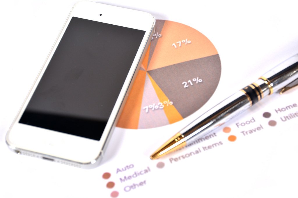 A person working through a household budget with a calculator, pen and notebook.