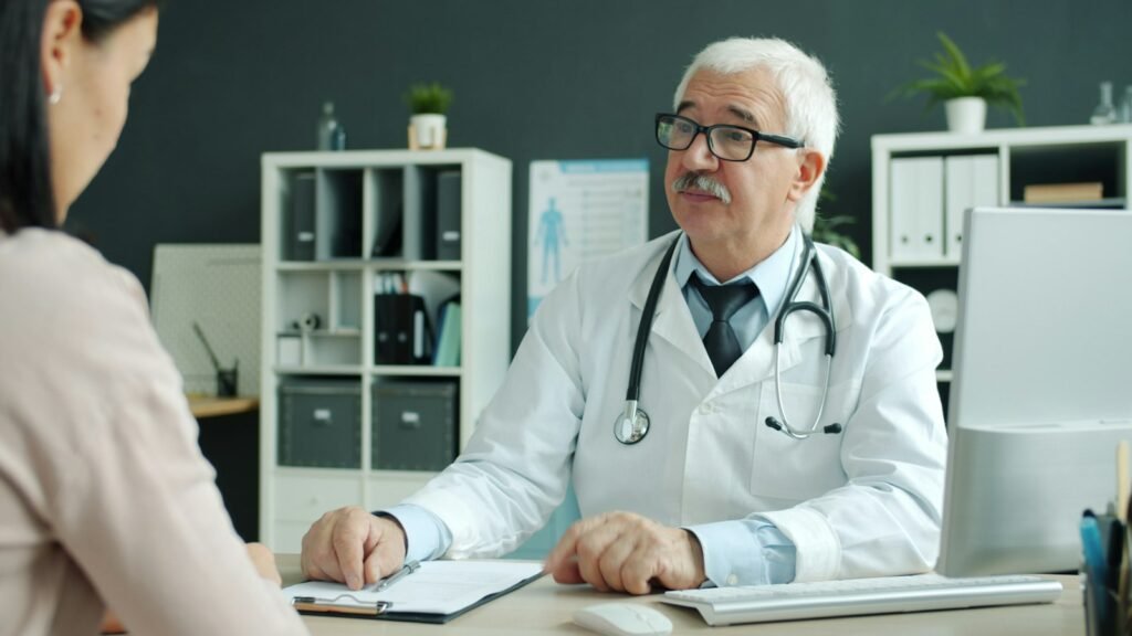 A doctor talking with a patient across a desk in a consulting room