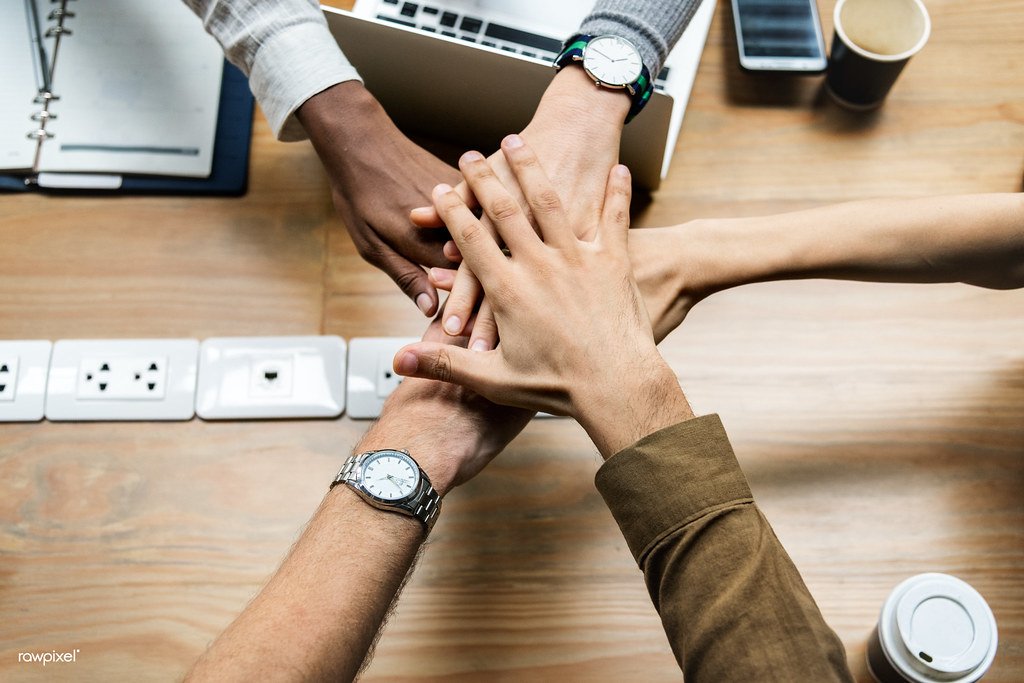 A team of business colleagues stacking their hands together to show unity and support.