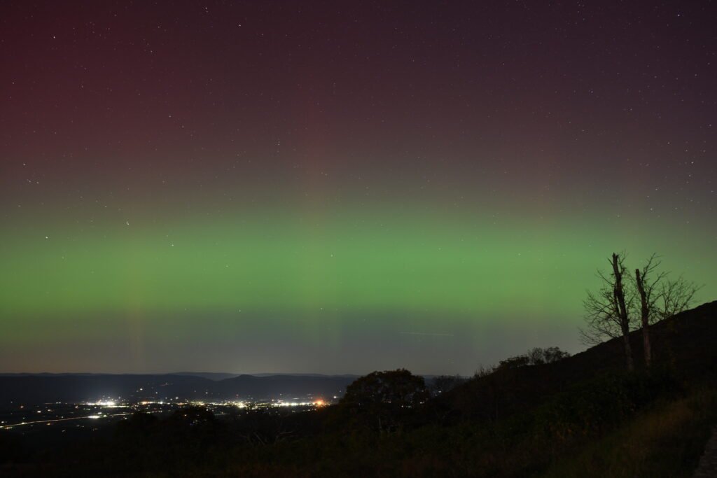 A vivid green aurora borealis display glowing across a dark night sky.