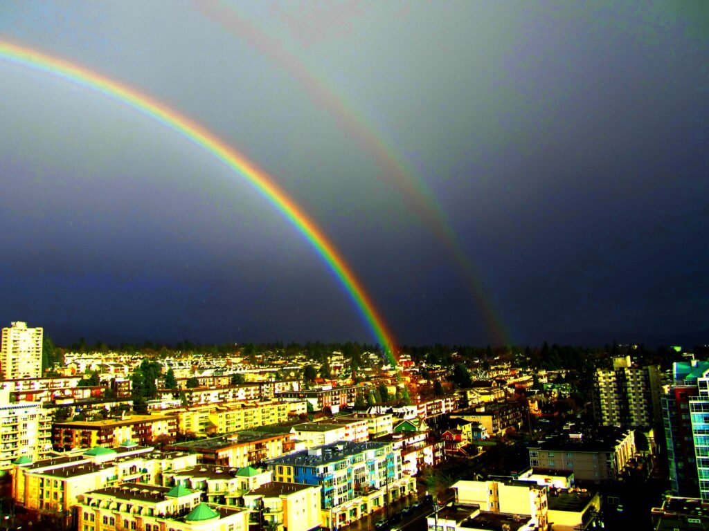 A bright double rainbow arcing across a stormy sky, showing the curved band of colors that gives rainbows their shape