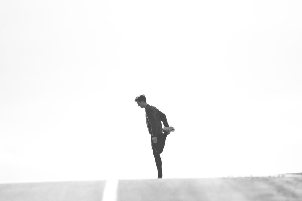 A person stretching before exercise, a habit linked to reducing post-workout muscle soreness.