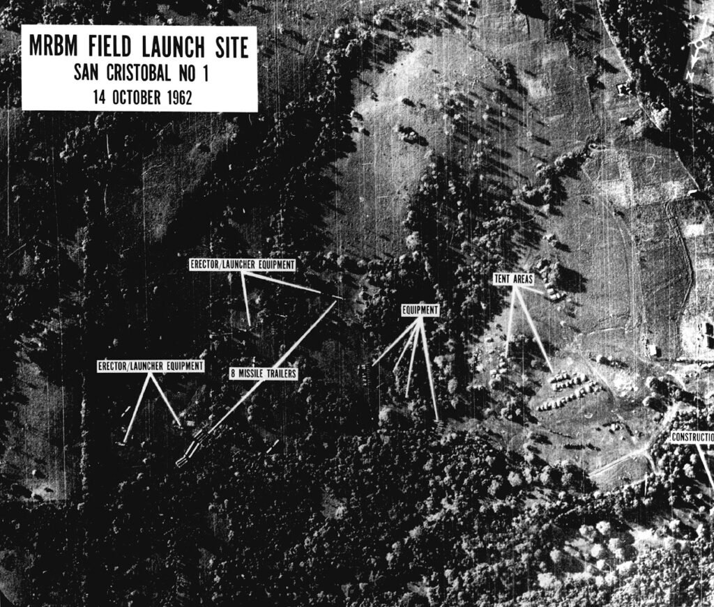 Grainy black-and-white aerial reconnaissance photograph showing missile transporters and fueling tents at a Soviet missile site under construction in Cuba.