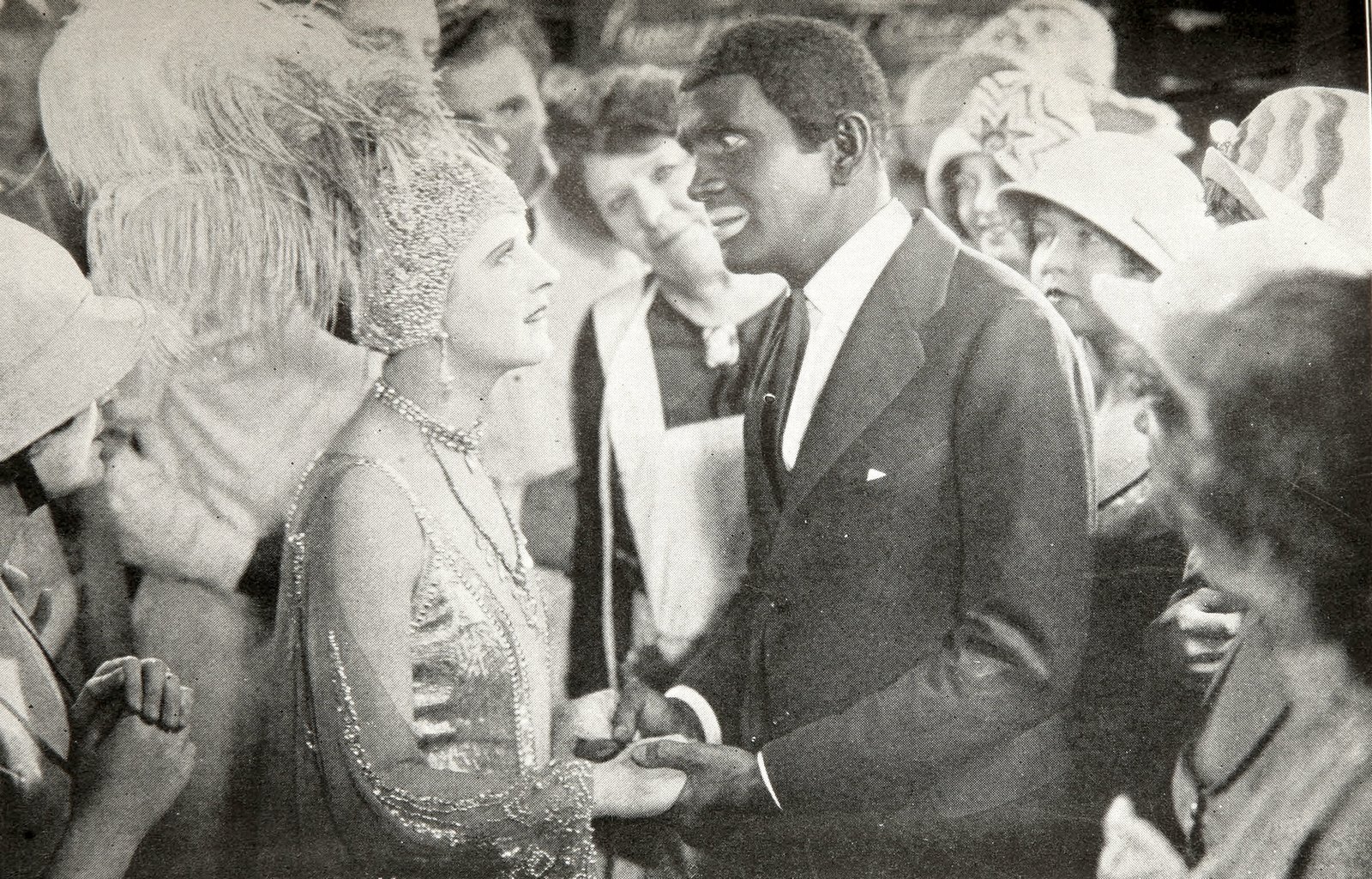 Black-and-white film still from The Jazz Singer (1927): Al Jolson, as Jack Robin, embraces May McAvoy, as Mary Dale, in a backstage scene.
