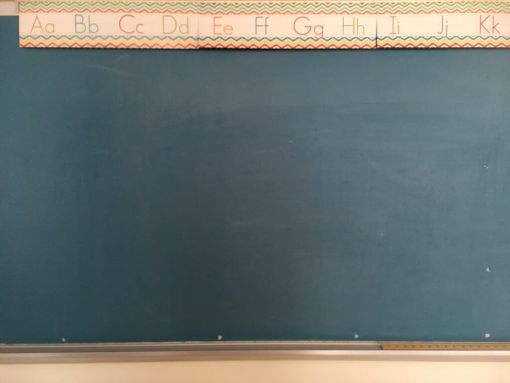 A classroom blackboard covered with handwritten letters